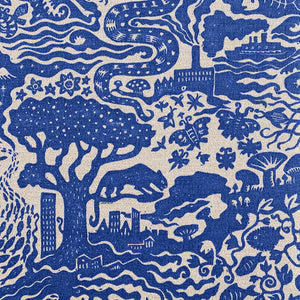 All Tomorrow’s Future linen by The Monkey Puzzle Tree in blue, a dense folk-art scene behind a sofa in a living room