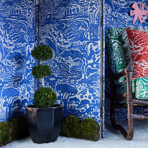 All Tomorrow’s Future linen by The Monkey Puzzle Tree in blue, a dense folk-art scene in a styled room setting
