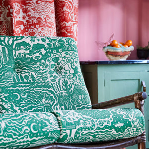 All Tomorrow’s Future linen by The Monkey Puzzle Tree in green, a dense folk-art scene upholstered on an armchair