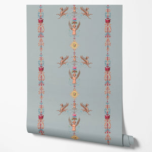 Angels and Suns wallpaper by Tatie Lou in grey, partly unrolled roll showing cherubs and suns in trails