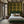 Gilded Wine wallpaper by Liberty James Studio in gold, green and red, an ornate mirrored design in a bedroom