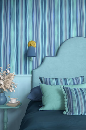 Bel Harbour wallpaper by Liberty James Studio in blue, varied stripes behind a bed