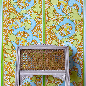 Blanche wallpaper by Claire de Quénetain in orange and green, a hand-painted floral design in a styled room setting