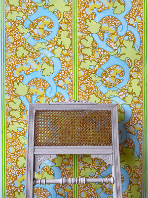 Blanche wallpaper by Claire de Quénetain in orange and green, a hand-painted floral design in a styled room setting