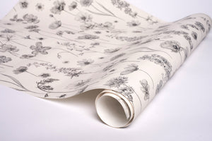 Botanica wallpaper by Victoria Sanders in cream, partly unrolled roll showing wildflowers and poppies
