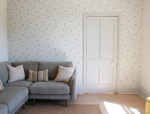 Caja Floral wallpaper by Seed Home Designs in grey, line-drawn daisies behind a sofa in a living room