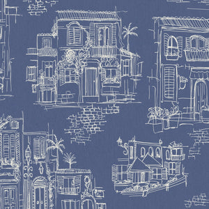 Charming Lanes wallpaper by Brand McKenzie in blue, toile-style townhouses behind a bed