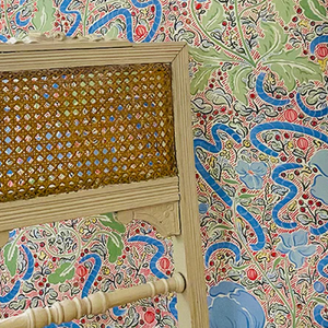 Axelle wallpaper by Claire de Quénetain in green and blue, a hand-painted floral design in a styled room setting