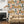 Connecting Frames wallpaper by Brand McKenzie in caramel, a gallery wall of framed portraits behind a sofa in a living room
