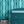 Deco Prism wallpaper by Liberty James Studio in teal, art deco wave stripes behind a console table