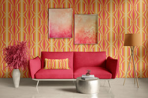 Deco Prism wallpaper by Liberty James Studio in orange, art deco wave stripes behind a sofa in a living room
