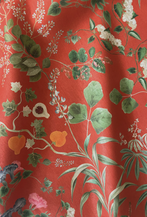 Little Eden linen by Deus ex Gardenia in orange, draped close-up of lush leaves and fruit