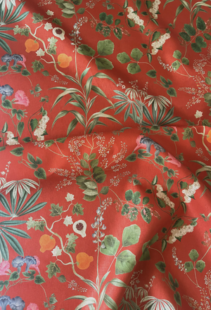 Little Eden linen by Deus ex Gardenia in orange, draped, showing lush leaves and fruit