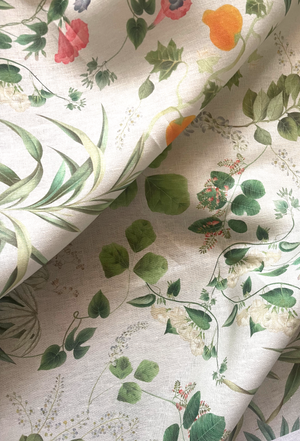 Little Eden linen by Deus ex Gardenia in cream and green, draped close-up of lush leaves and fruit