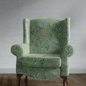 Little Eden velvet by Deus ex Gardenia in sage green, lush leaves and fruit upholstered on an armchair