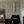 Little Eden wallpaper by Deus ex Gardenia in cream and green, lush leaves and fruit behind a sofa in a living room