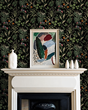 Little Eden wallpaper by Deus ex Gardenia in black, lush leaves and fruit around a fireplace