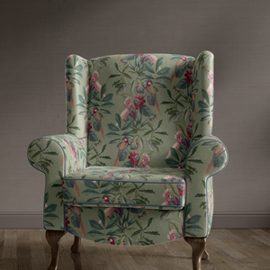 Passiflora velvet by Deus ex Gardenia in sage green, parrots and passion flowers upholstered on an armchair