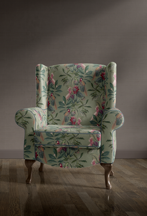Passiflora velvet by Deus ex Gardenia in sage green, parrots and passion flowers upholstered on an armchair