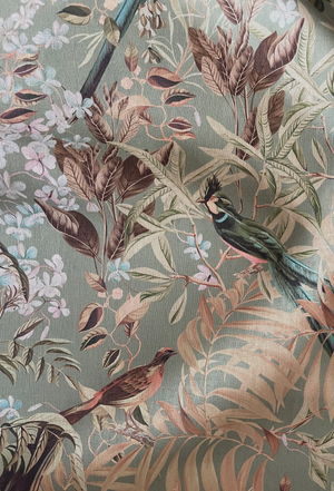 Resplendent Woods linen by Deus ex Gardenia in sage green, in soft folds showing peacocks and pheasants in trees