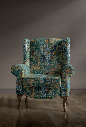 Resplendent Woods velvet by Deus ex Gardenia in dark green, peacocks and pheasants in trees upholstered on an armchair