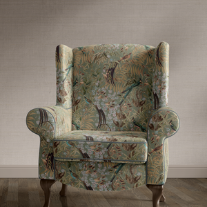 Resplendent Woods velvet by Deus ex Gardenia in sage green, peacocks and pheasants in trees upholstered on an armchair