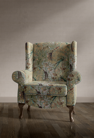 Resplendent Woods velvet by Deus ex Gardenia in sage green, peacocks and pheasants in trees upholstered on an armchair