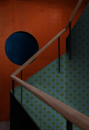 Little Palma wallpaper by Deus ex Gardenia in dark green, rows of palm trees in a hallway