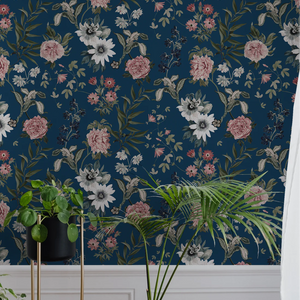Beechcroft Garden wallpaper by Deus ex Gardenia in navy, garden flowers and foliage behind a sofa in a living room