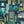 Downtown Deco wallpaper by Brand McKenzie in teal, Art Deco skyscrapers behind a sofa in a living room
