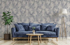 Eden wallpaper by Victoria Sanders in blue, birds among foliage behind a sofa in a living room