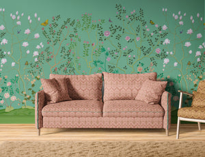 Eden Garden wallpaper by Dami and Em Design in green, a chinoiserie garden behind a sofa in a living room