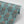 Fleur wallpaper by Tatie Lou in teal, partly unrolled roll showing stylised flower sprays