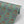 Fleur wallpaper by Tatie Lou in sage green, partly unrolled roll showing stylised flower sprays