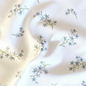 Forget Me Not fabric by Seed Home Designs in blue and green, draped, showing scattered forget-me-nots