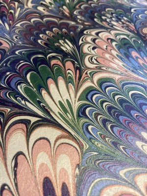 Serpentine wallpaper by House of Amitié in pink and blue, partly unrolled roll showing peacock-feather marbling