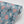 Honiton Lace wallpaper by Annika Reed in blue and pink, partly unrolled roll showing lace-style flowers