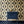 Hourglass wallpaper by Liberty James Studio in navy and gold, a retro hourglass wave behind a console table