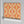 Hourglass wallpaper by Liberty James Studio in orange and pink, partly unrolled roll showing a retro hourglass wave