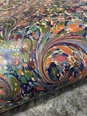 Dusk Tourmaline wallpaper by House of Amitié in purple and green, sample roll showing hand-marbled swirls