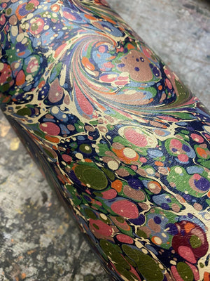 Dusk Tourmaline wallpaper by House of Amitié in purple and green, partly unrolled roll showing hand-marbled swirls