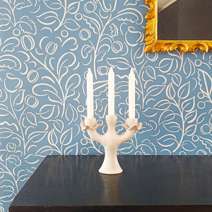 Celeste wallpaper by Claire de Quénetain in blue, swirling leaf scrolls above a sideboard