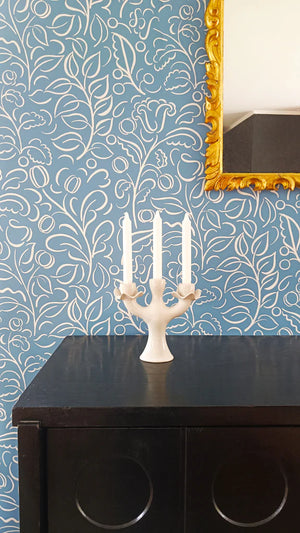 Celeste wallpaper by Claire de Quénetain in blue, swirling leaf scrolls above a sideboard