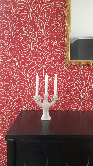 Celeste wallpaper by Claire de Quénetain in red, swirling leaf scrolls behind a console table