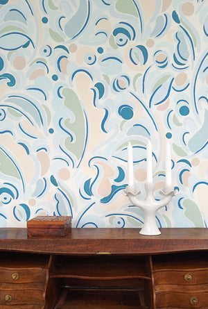 Gloria wallpaper by Claire de Quénetain in blue, scattered leaves behind a console table