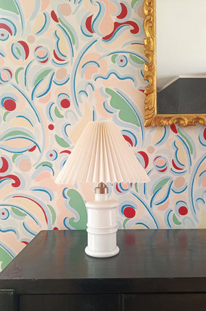 Gloria wallpaper by Claire de Quénetain in red, scattered leaves above a sideboard