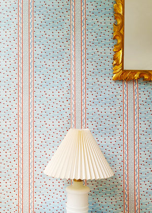 Mia wallpaper by Claire de Quénetain in red, fine stripes behind a console table