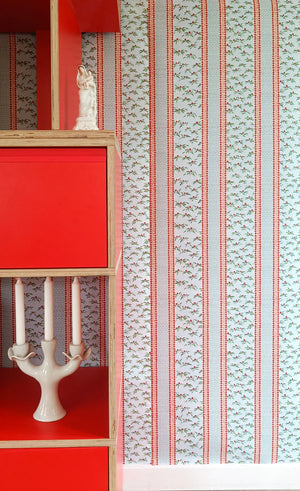 Hélène Red wallpaper by Claire de Quénetain in blue and red, striped bands above a sideboard
