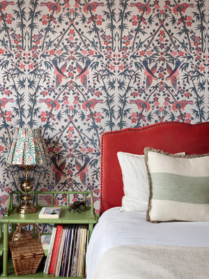 Palamara wallpaper by Deus ex Gardenia in blue and red, mirrored birds and flowers behind a bed