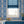 Marco Island wallpaper by Liberty James Studio in blue, a scrolling damask design behind a bed